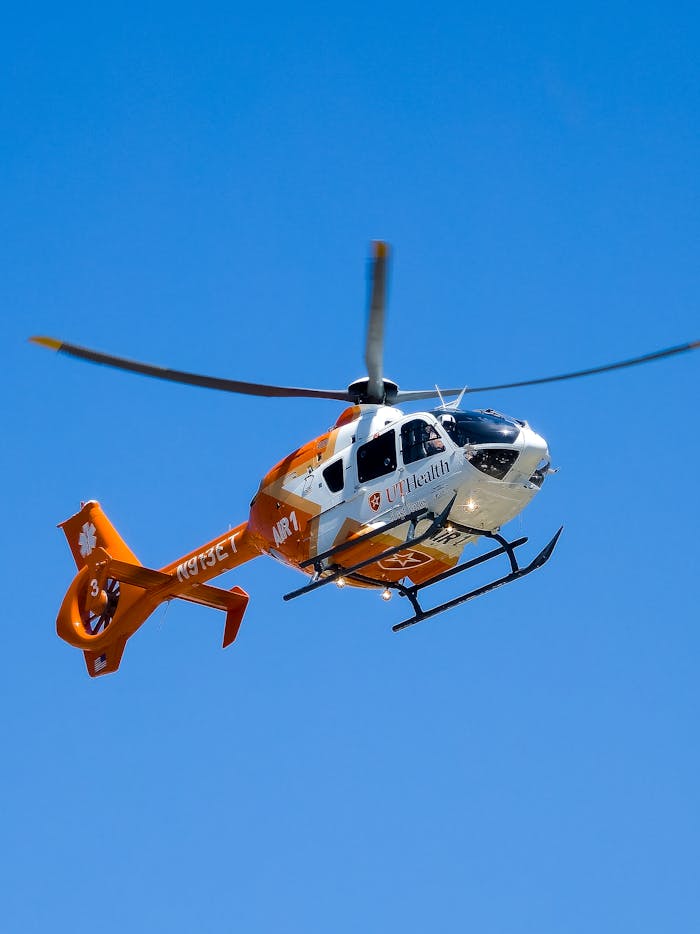 A rescue helicopter in flight against a clear blue sky, showcasing aviation and emergency services.