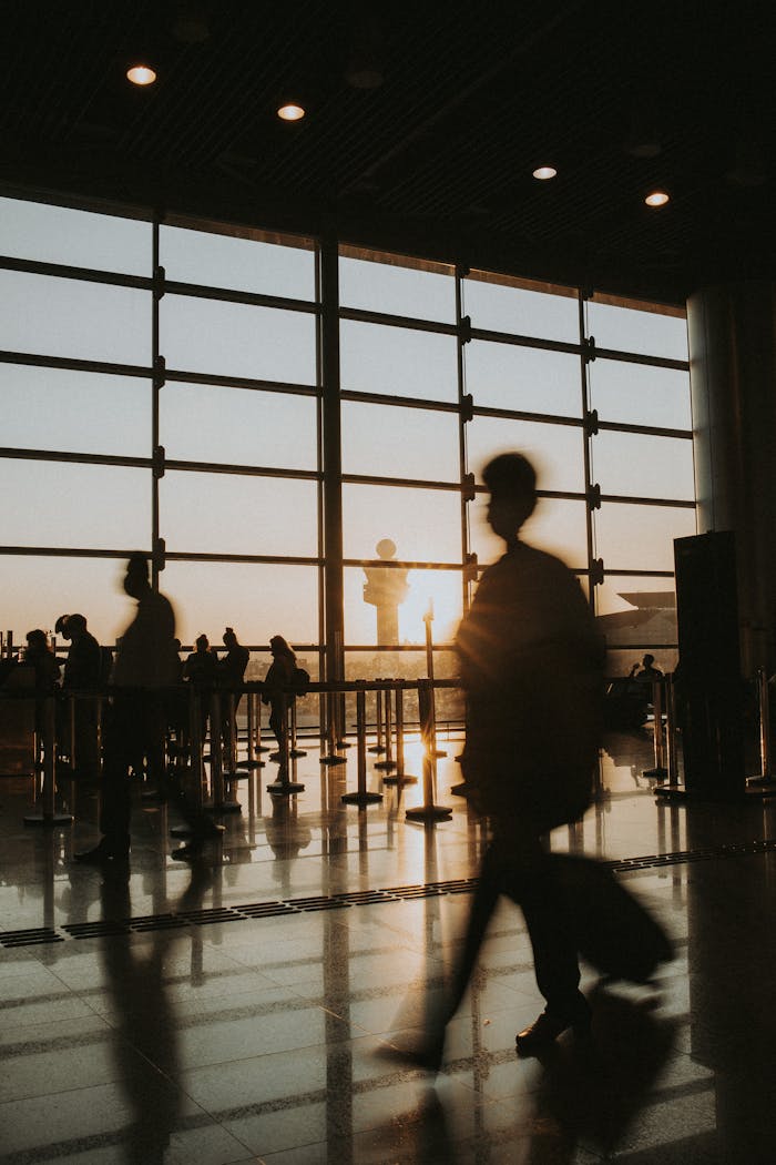 services-img Passengers silhouetted against sunrise in an airport terminal, capturing the essence of travel.